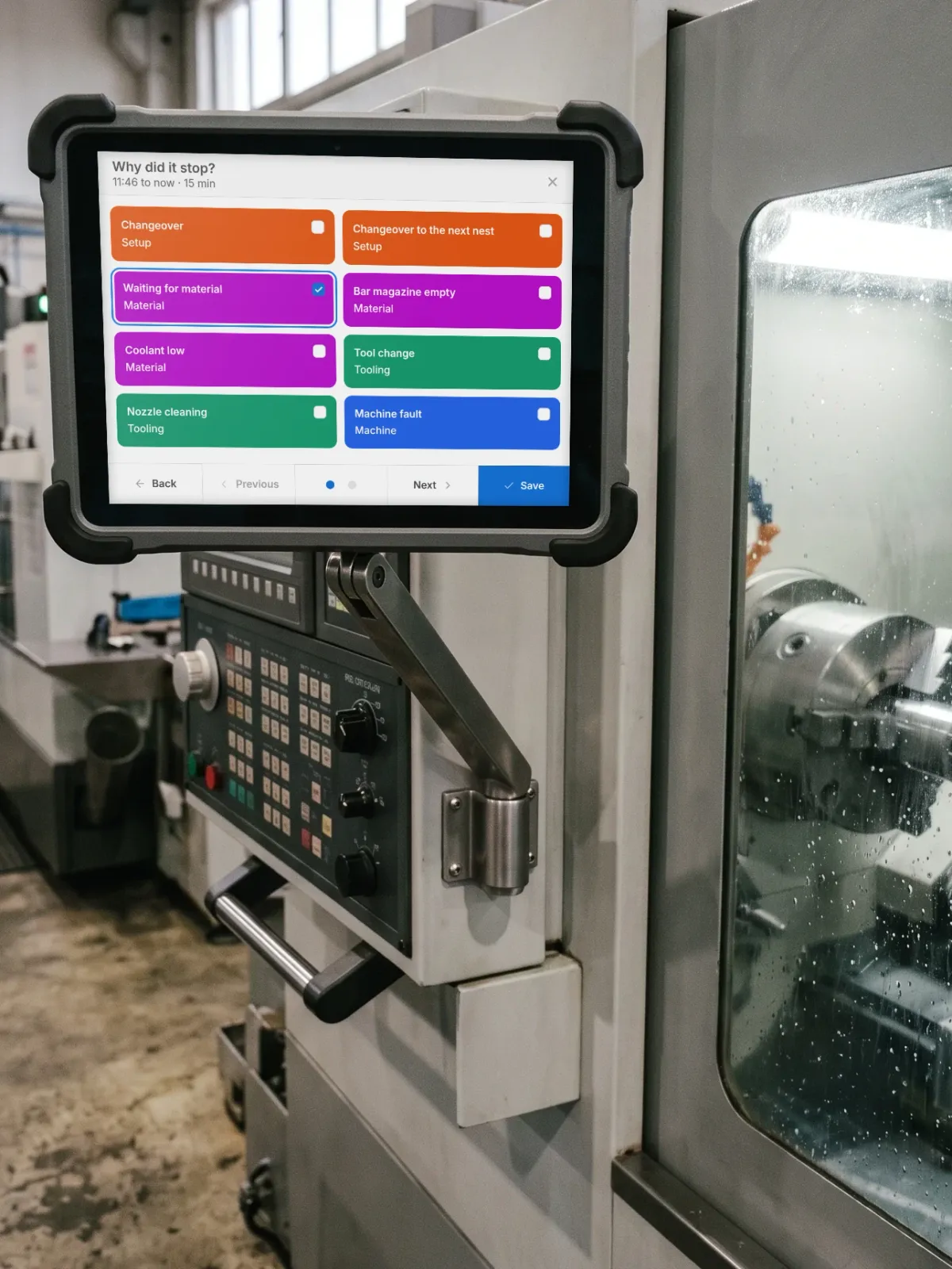 A tablet beside a CNC lathe asking why it stopped, with the plant's own reasons to tap and Waiting for material picked.